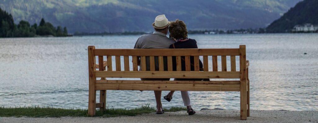 Two pensioners sitting on a bench overlooking a lake, for the Nordic vs UK pension systems comparison